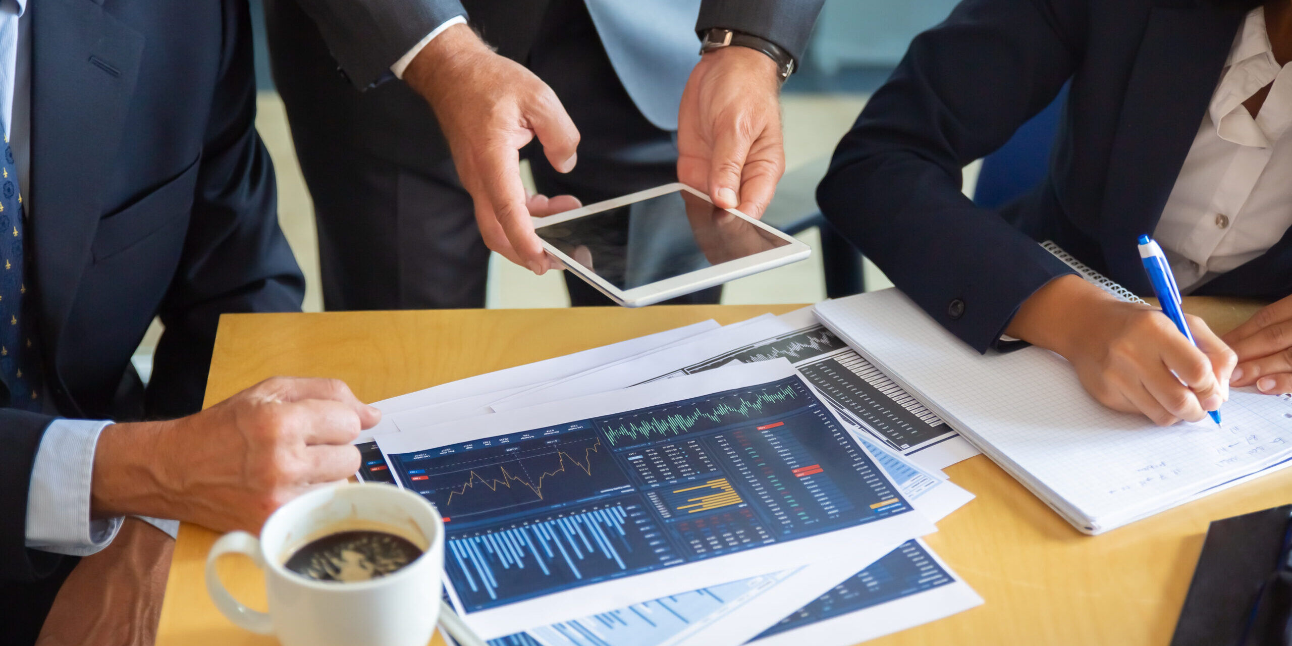 Unrecognizable business partners working with statistic charts. Businessman holding tablet. Professional content businesswoman making notes for statistics. Communication and partnership concept